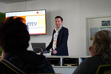 Präsentation vor Publikum mit Bildschirm im Hintergrund zur Übungsfirma „crtv H media solutions“.