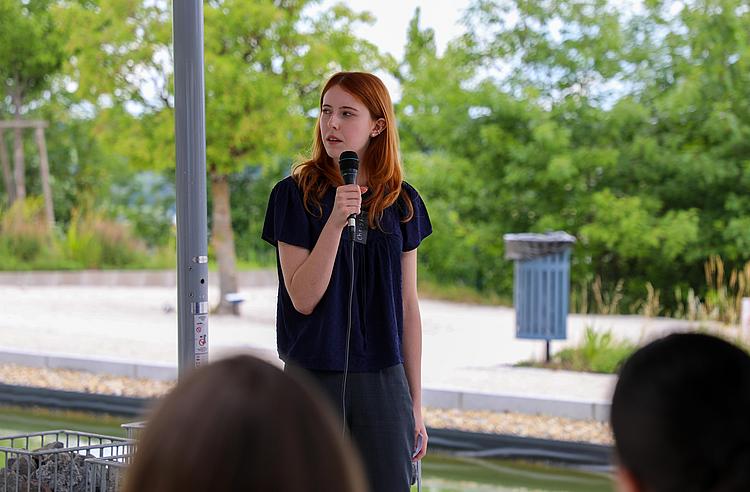 Christina Fuchs präsentiert vor einer Stellwand das Nachhaltigkeitsprojekt „Blattlos glücklich“ der Eckert Schulen.