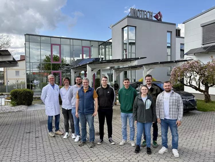 Mehrere Menschen stehen vor einem Gebäude.