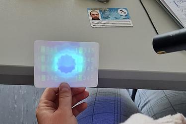 Eine Ausweiskarte wird unter UV-Licht geprüft. Sichtbar werden Sicherheitsmerkmale, die bei der Echtheitsprüfung von Dokumenten eine wichtige Rolle spielen.
