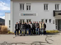 Teilnehmer des Lehrgangs stehen vor dem Firmengebäude von Bischof + Klein und posieren für ein Gruppenfoto.