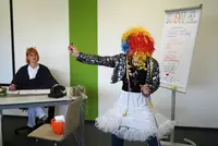 Bunt verkleidete Person zeigt einen Gegenstand.