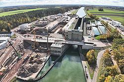 Luftaufnahme einer Schleusenanlage mit Baustelle, Brücken, Kränen und Wasserstraße in ländlicher Umgebung.
