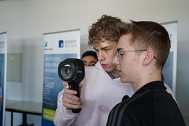 Zwei Jugendliche betrachten gemeinsam eine Wärmebildkamera und analysieren deren Anzeige.