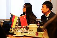 Zwei Mitglieder der chinesischen Delegation sitzen an einem Konferenztisch bei den Eckert Schulen in Regenstauf. Im Vordergrund stehen die deutsche und die chinesische Tischflagge.
