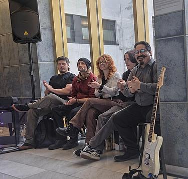 Mitglieder der Schulband des BFW Eckert sitzen nebeneinander und applaudieren während einer musikalischen Veranstaltung.