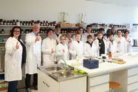 Gruppe von Schülern und Lehrkräften im Labor zeigt Daumen hoch.