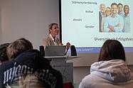 Dozentin präsentiert Inhalte im Seminarraum und spricht über Diversität als Erfolgsfaktor.