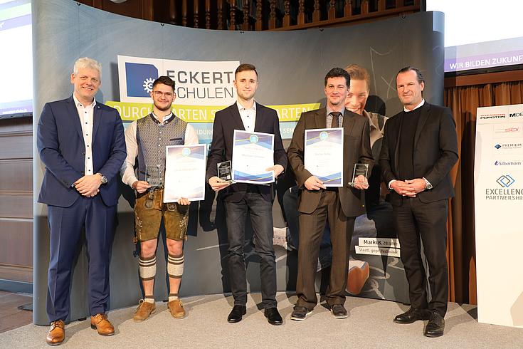 Vorstandsvorsitzender Alexander Eckert Freiherr von Waldenfels (links) verlieh gemeinsam mit Markus Johannes Zimmermann (Schulleiter und Geschäftsführer der Dr. Eckert Akademie, rechts) die Eckert Trophy für Bestnoten von 1,5 oder besser. (Foto: Eckert Schulen)