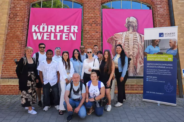 Klasse steht vor einem pinken Hintergrund mit der Aufschrift "Körperwelten".