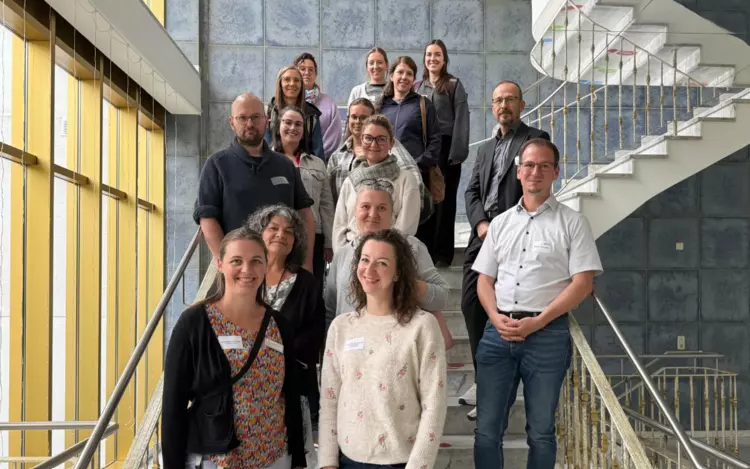 Gruppenfoto der Teilnehmenden des Besuchs der Sozialdienste am BFW Eckert – aufgenommen im Treppenhaus des Campus. Die Gäste und Gastgeberinnen und Gastgeber stehen lächelnd auf der Treppe und blicken in die Kamera.