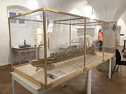Seitliche Ansicht eines großen römischen Schiffsmodells in einer Glasvitrine.