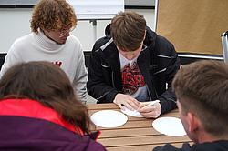 Kleingruppe arbeitet konzentriert an Aufgaben und hält Ergebnisse schriftlich fest.