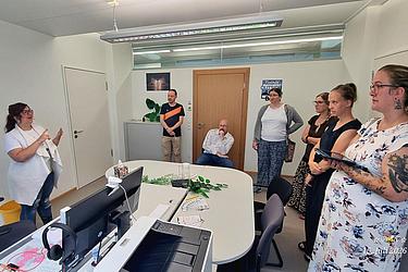Teilnehmende stehen in einem Büroraum und hören einer Person zu, die den Ablauf des Action-Bounds erklärt.