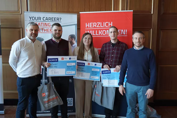 Vertreter der Würth Elektronik Gruppe und der Eckert Schulen gratulieren den Gewinnerinnen und Gewinnern eines Wettbewerbs. Drei Teilnehmende halten symbolische Schecks für den 1., 2. und 3. Platz, während sie gemeinsam vor Roll-ups von Würth Elektronik und den Eckert Schulen stehen.