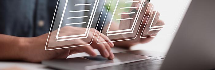 Hände tippen auf Laptop – eingeblendete Symbole von digitalen Dokumenten