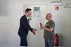 Zwei Personen bei der Übergabe eines Zertifikats im Rahmen einer Veranstaltung.