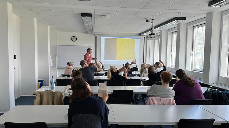 In einem Seminarraum prüfen Teilnehmende Dokumente und Sicherheitsmerkmale während einer Schulung. Die Szene zeigt den praktischen Austausch und die aktive Auseinandersetzung mit dem Thema Dokumentensicherheit.