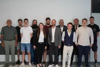 Gruppenfoto bei der Projektbesprechung Gruppenfoto von sechs Personen in unterschiedlicher Business-Kleidung vor einer weiß gestrichenen Wand mit dekorativen Farbstreifen. Alle stehen nebeneinander und lächeln in die Kamera.
