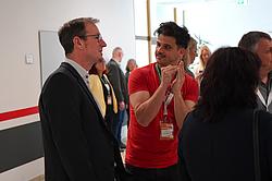 Zwei Teilnehmende im Austausch während der Veranstaltung, weitere Personen im Hintergrund.