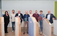 Die angehenden Holztechniker halten ihre Ausarbeitung in den Händen und lachen zufrieden in die Kamera.