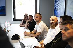 Eine Gruppe von Personen wirft aufmerksam ihren Blick nach vorne. Die Gruppe wirkt interessiert. 
