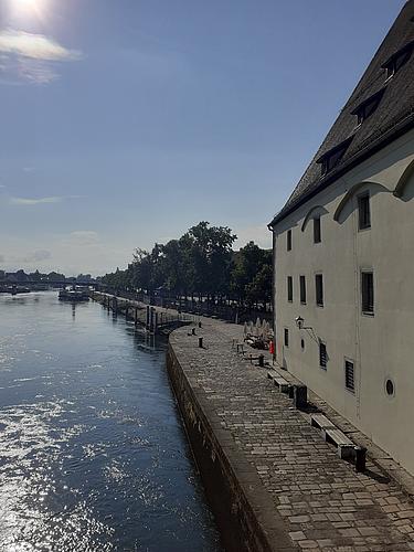 Donaupromenade in Regensburg bei Sonnenlicht mit Blick auf das Welterbe-Gebäude und die Anlegestellen