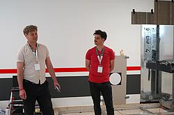 Zwei Personen stellen ein Projekt oder Gerät in einem Raum vor.