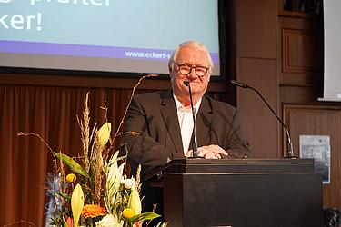 Gerald Saule bei der Begrüßung zur Absolventenfeier 2026 Ein älterer Mann mit Brille steht am Rednerpult der Eckert Schulen und begrüßt die Gäste einer Veranstaltung.