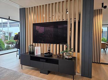 Innenraum eines Musterhauses mit moderner Medienwand und Raumgliederung als Beispiel für die Umsetzung planerischer Konzepte.