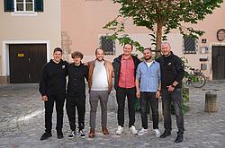 Mehrere Absolventen des Industriemeister-Lehrgangs stehen gemeinsam lachend vor einem Baum auf einem Innenhof.