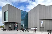Modernes Museumsgebäude des Hauses der Bayerischen Geschichte in Regensburg mit markanter Architektur aus Beton und Glas unter bewölktem Himmel.