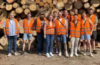 Binderholz Tirol Gruppe der Holztechnik-Studierenden mit Sicherheitswesten vor Holzstapeln bei der Firma Binderholz.