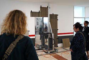 Mehrere Personen beobachten einen Wanddrucker bei der Umsetzung eines Drucks.