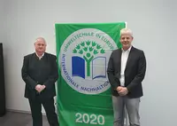 Markus Johannes Zimmermann (Geschäftsführer und Schulleiter der Dr. Eckert Akademie, rechts) und Gerald Saule (Head of Vocational Training International und Umweltbeauftragter) nahmen die traditionell mit der Auszeichnung verliehene Flagge am Campus Regenstauf entgegen.