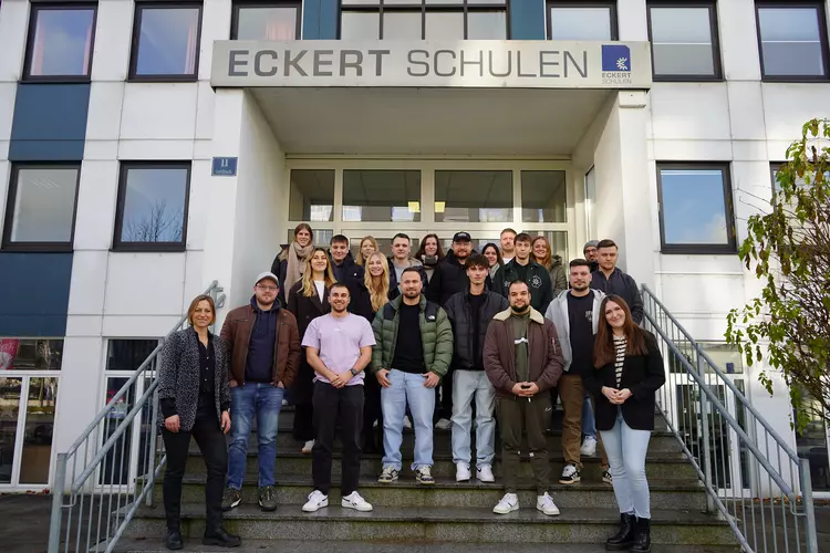 Wirtschaftsfachwirt Kursstart 12 2025 Eine Gruppe von rund zwanzig angehenden Wirtschaftsfachwirten steht auf der Treppe vor dem Haupteingang der Eckert Schulen in Regensburg und lächelt in die Kamera.