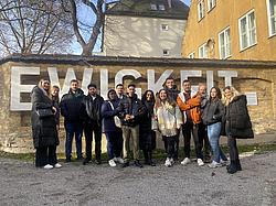 Exkursion Augsburg 07 Teilnehmende eines allgemeinen Integrationskurses der Eckert Schulen stehen gemeinsam vor dem Schriftzug „Ewigkeit“ in der Fuggerei Augsburg.