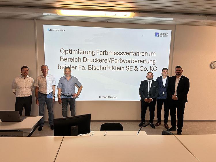 Angehende staatlich geprüfte Techniker der Eckert Akademie Regenstauf präsentieren die Ergebnisse ihrer praxisnahen Projektarbeiten vor einer Präsentationsfläche.