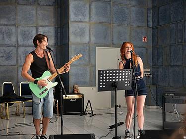 Schulband, BFW Eckert, Musikveranstaltung, Musikergruppe, Publikum, Applaus, musikalisches Engagement, Bandmitglieder, Gemeinschaft, Musikprojekt