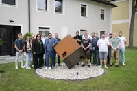 Gruppenbild vor dem Gebäude der Beraten + Planen Gruppe, im Vordergrund ein großer Hauswürfel aus Stahl als Skulptur.