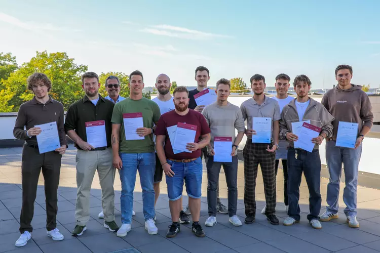 Einige Männer machen gemeinsam mit Zertifikat in der Hand ein Gruppenfoto