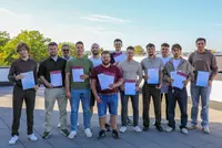 Einige Männer machen gemeinsam mit Zertifikat in der Hand ein Gruppenfoto