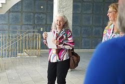 Person spricht in einer Gruppe und hält Unterlagen in der Hand, lockere Gesprächssituation.