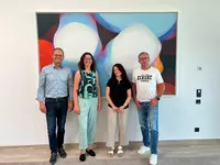 Vier Personen stehen vor einem großformatigen Kunstwerk in den Räumen der Eckert Schulen.