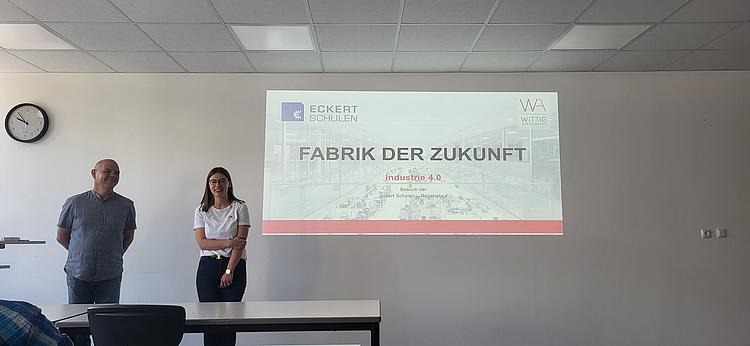 Zwei Vortragende stehen vor einer Präsentationsfolie zum Thema „Fabrik der Zukunft“ im Klassenraum der Eckert Schulen