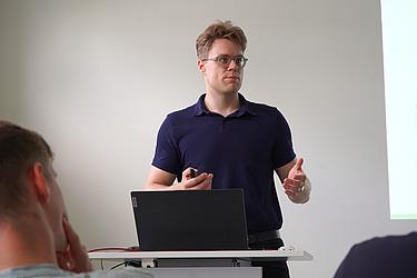 Ein Teilnehmer präsentiert vor der Gruppe und erklärt seine Ausarbeitung im Rahmen der Projektvorstellung.