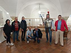 Gruppe von Erwachsenen steht vor einem ausgestellten Modell eines römischen Schiffes im Museum.