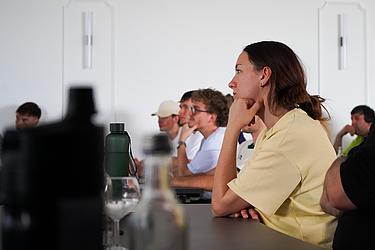 Teilnehmende verfolgen aufmerksam den Infoabend zum Austauschprogramm China. Im Vordergrund sitzt eine junge Frau konzentriert an einem Tisch.