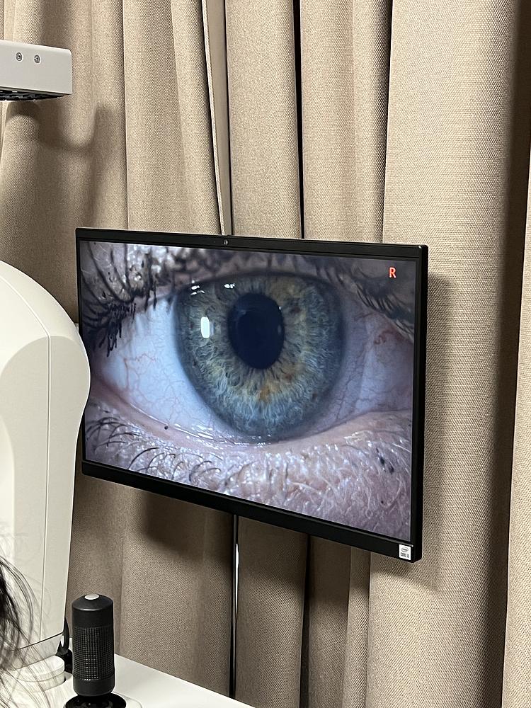 Nahaufnahme eines Auges auf einem Monitor während einer digitalen Augenuntersuchung in einem Optikgeschäft.