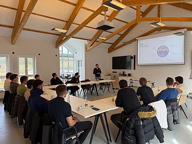 Teilnehmer eines Industriemeister-Lehrgangs sitzen in einem modernen Seminarraum und verfolgen aufmerksam eine Präsentation zur Kunststoffproduktion.